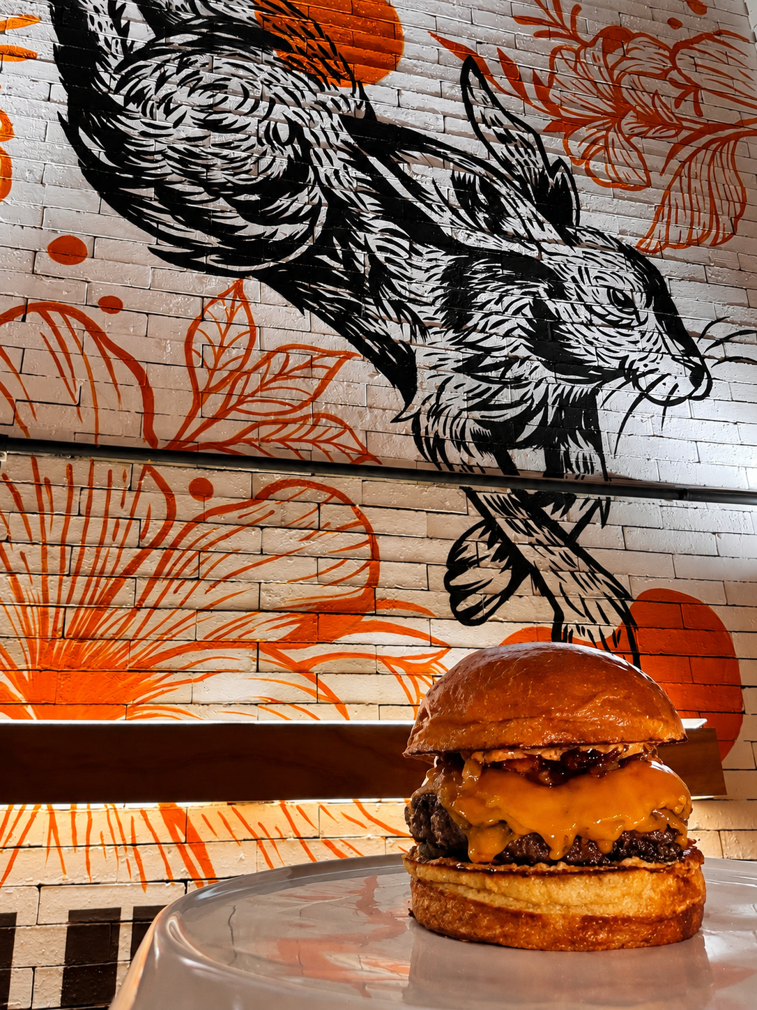 Mural de la liebre en la pared del restaurante con una cheeseburger La Liebre